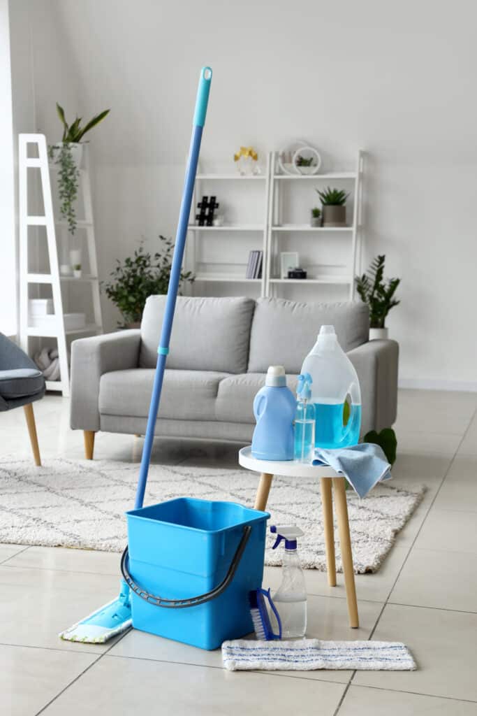 Matériel de Nettoyage Moderne : Prêt à Moper Matériel de nettoyage bleu (seau, balai-serpillière, produits) prêt à l'emploi sur sol carrelé dans un salon moderne.